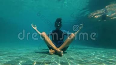 慢动作水下拍摄一个年轻人在瑜伽<strong>姿势</strong>冥想<strong>游泳</strong>池底部。 他被